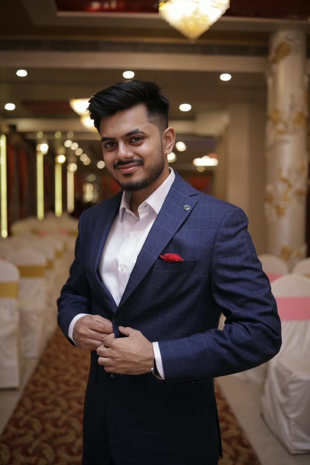 A smiling man in a navy suit with a red pocket square