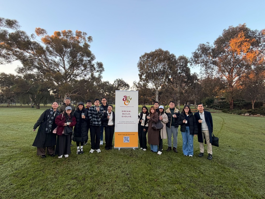 A large group of members gathered with the Ambitious Growth Circle banner in the park