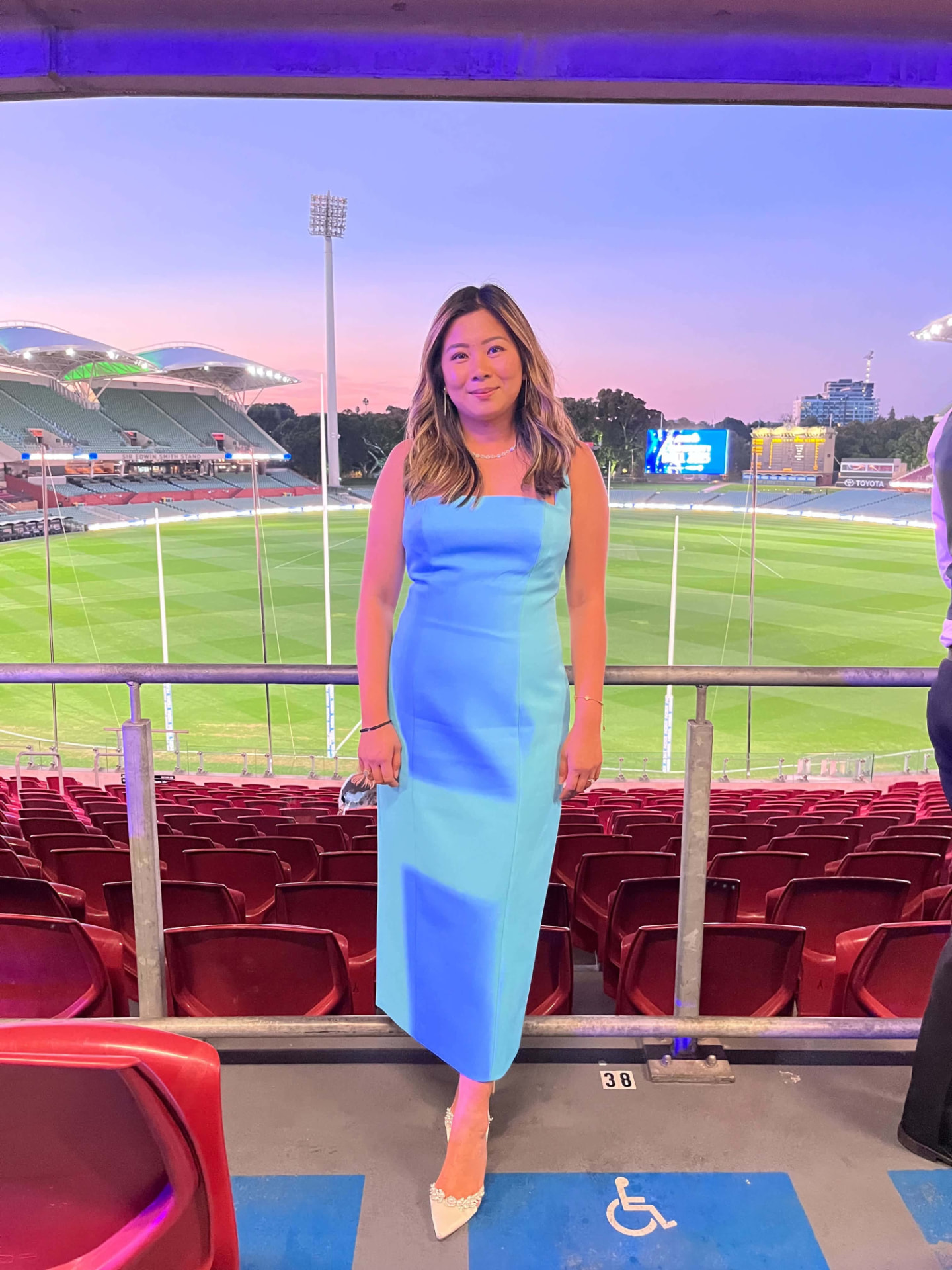A woman in a blue dress at Adelaide Oval at dusk