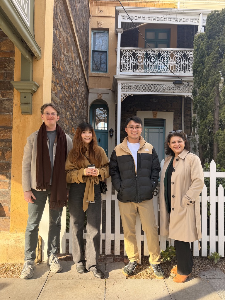 Four friends smiling together in front of Adelaide terrace houses