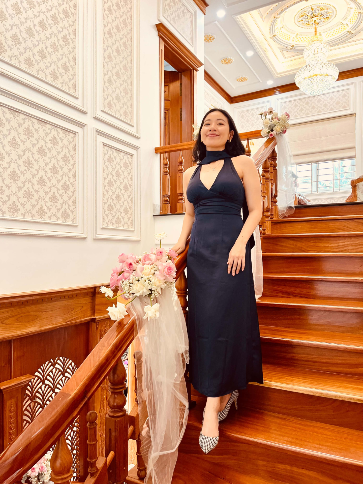 A woman in a navy dress standing on a wooden staircase
