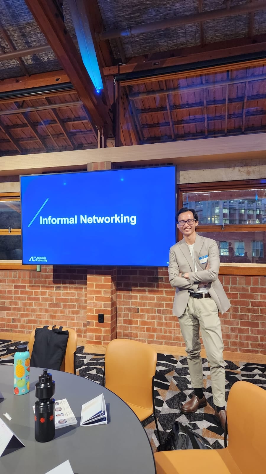 A smiling young professional in a light suit at a networking event